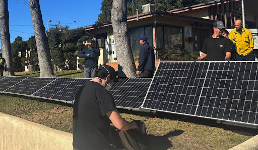 Workers installing a ground-mounted solar panel array outdoors